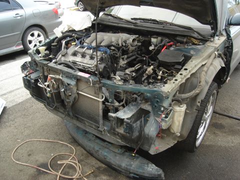 1995 Mazda MX-6 - The front end of a car has been disassembled, exposing the engine and cooling system for maintenance or repair.