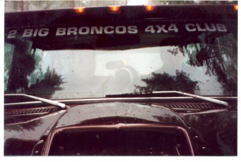 1989 Ford Bronco - Vehicle windshield shows a sticker for '2 BIG BRONCOS 4X4 CLUB' and reflections of trees and sky.