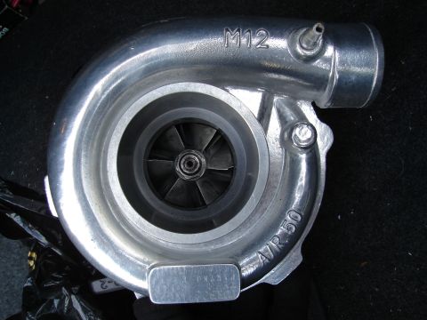 1995 Mazda MX-6 - A silver turbocharger with visible fan blades is shown against a dark background.