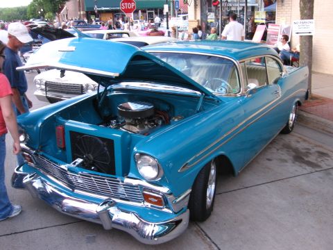 1989 Ford Mustang - A vibrant blue 1956 Chevrolet Bel Air is displayed with its hood open at a car show.