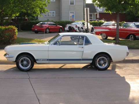 1989 Ford Mustang - Side view of a white 1965 Ford Mustang GT 200 coupe with blue racing stripes.