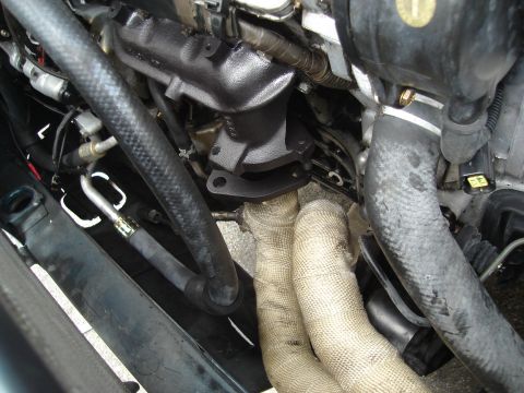 1995 Mazda MX-6 - Close-up view of engine components, including exhaust manifold and hoses.