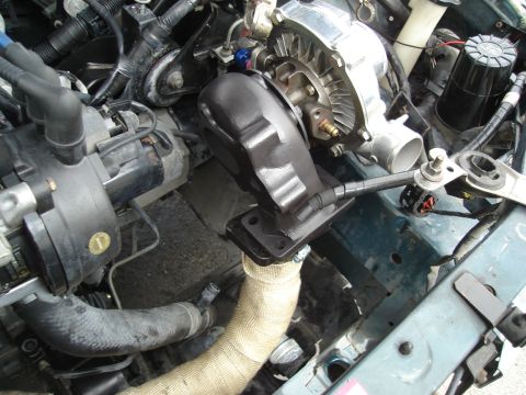 1995 Mazda MX-6 - Close-up view of a turbocharger being fitted into the engine bay of a vehicle.