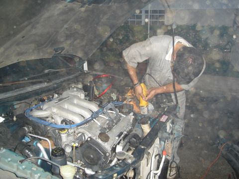 1995 Mazda MX-6 - Man working on the engine of a 1995 Mazda MX-6 with an angle grinder.
