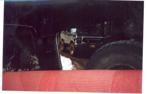 1989 Ford Bronco - View from inside a vehicle shows a 1970s Ford Bronco on a dirt road.