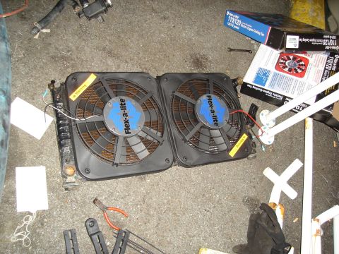 1995 Mazda MX-6 - Dual electric cooling fans and radiator assembly, with associated parts and packaging, lying on a concrete surface.
