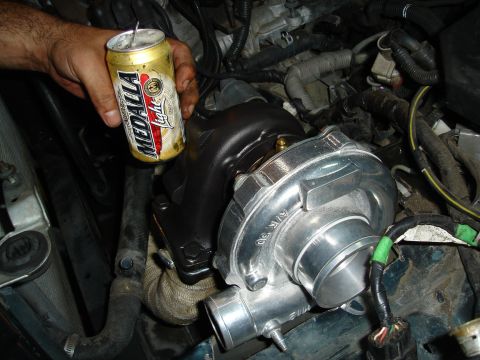 1995 Mazda MX-6 - A turbocharger is being installed in the engine bay, with a beer can held for size comparison.