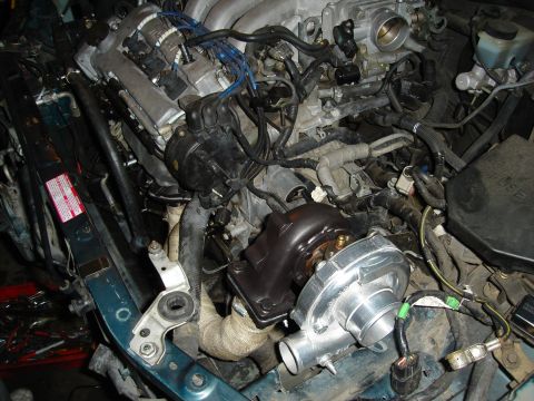 1995 Mazda MX-6 - Aftermarket turbocharger installed in an engine bay, with exhaust manifold and associated plumbing visible.