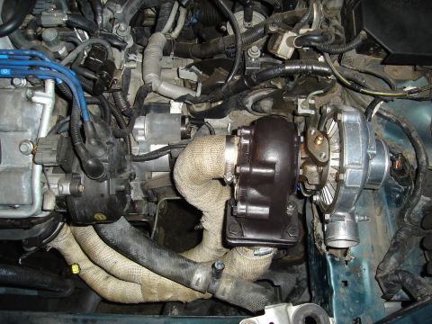 1995 Mazda MX-6 - Close-up view of a turbocharger system installed in a vehicle's engine bay.