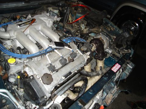 1995 Mazda MX-6 - Engine bay view of a Mazda V6 engine, a turbocharger setup and various engine components.