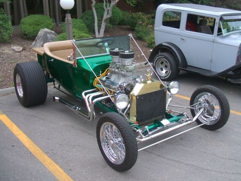 1974 Ford Ranchero - A custom green hot rod sits in a parking lot next to a gray sedan.
