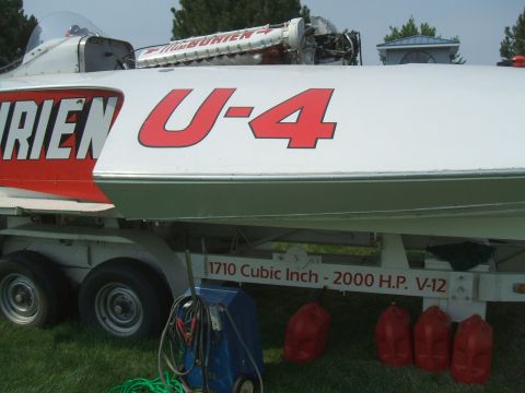1974 Ford Ranchero - A white and red boat, marked U-4, is displayed on a trailer with its engine exposed and several red fuel cans nearby.