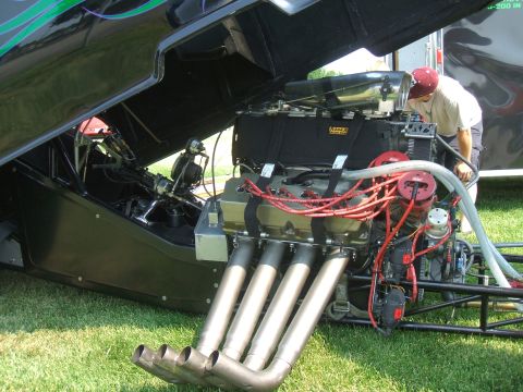 1974 Ford Ranchero - The powerful engine of a drag car is exposed for inspection, with a man checking its components.
