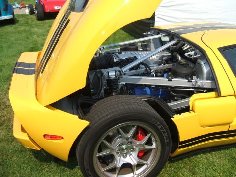 1974 Ford Ranchero - A yellow sports car displays its engine with the hood open, parked on grass at an outdoor event.