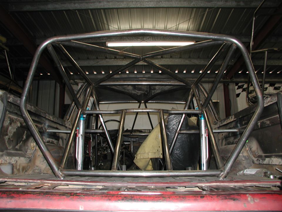Bare-metal tube roll cage built inside a vehicle interior in a shop