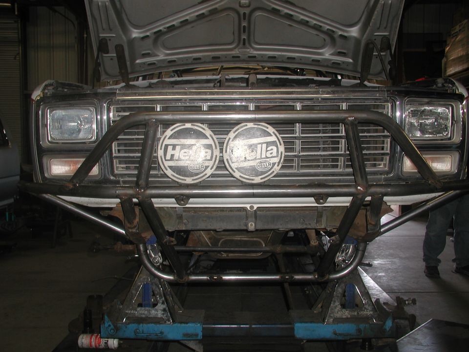 Front of a truck with custom tube bumper and two Hella lights on a lift