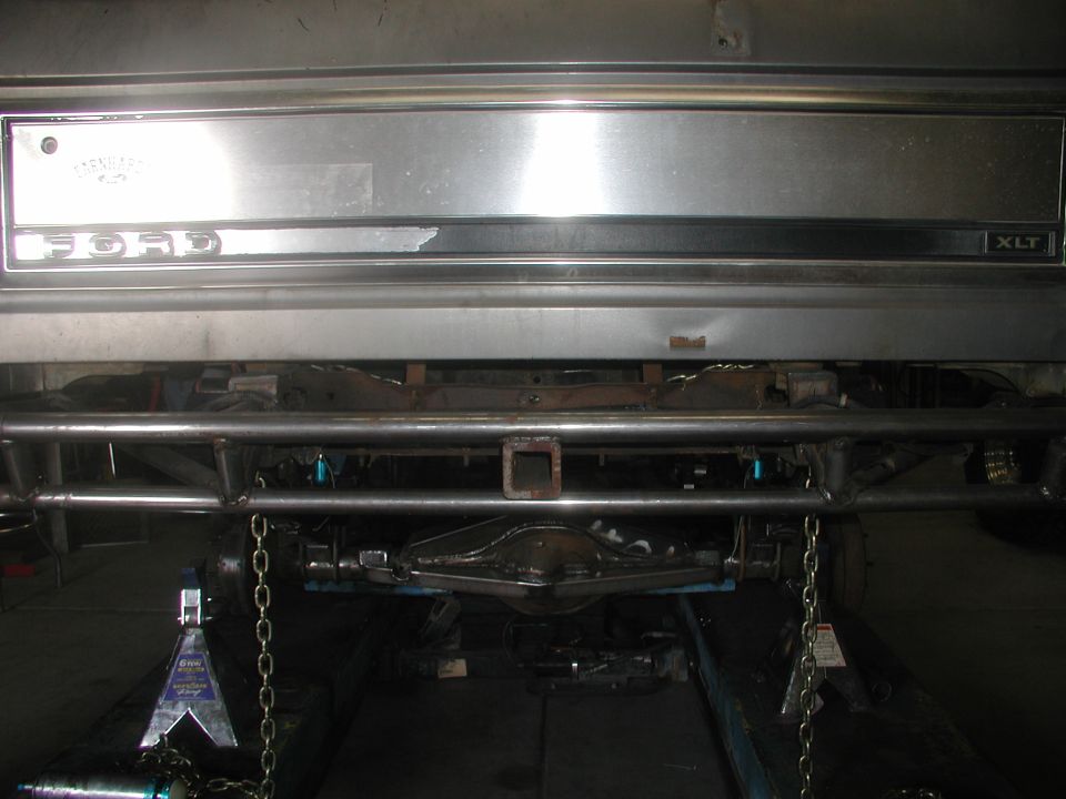 Rear tailgate of a Ford XLT truck with chrome bumper viewed in a shop