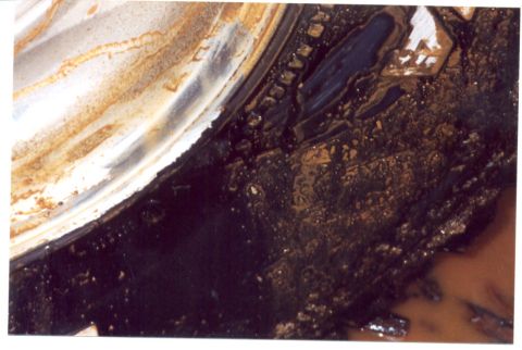1989 Ford Bronco - This close-up shows the heavily rusted and dirty undercarriage of a vehicle, with various metal components obscured by grime.
