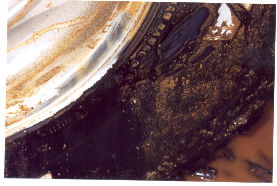 Close-up of oil-soaked greasy metal part with heavy black sludge