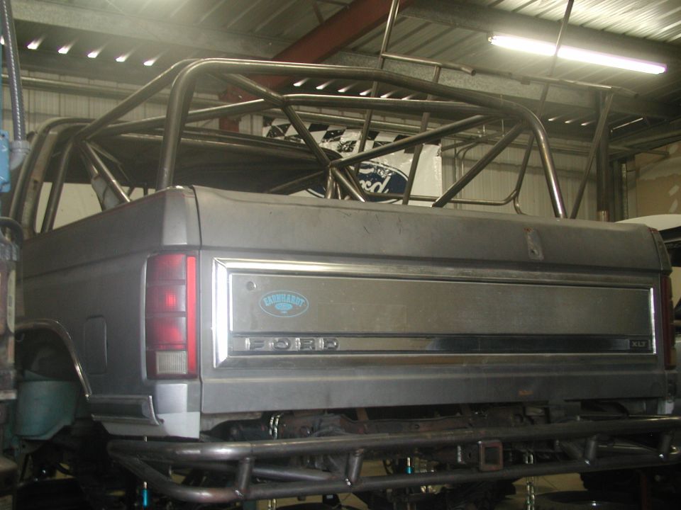 Rear of a Ford truck cab and bed with roll cage on a lift