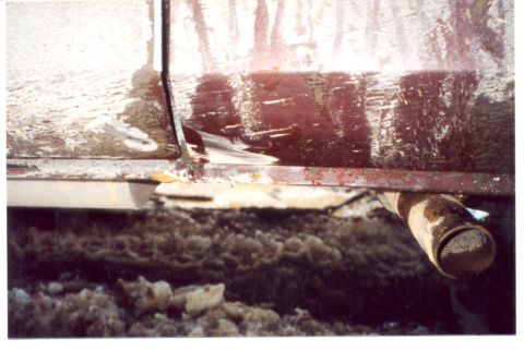 1989 Ford Bronco - A close-up side view of a 1989 Ford Bronco reveals significant rust and damage to its lower body and exhaust.