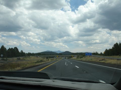 1993 Ford Taurus - View from a car driving on a highway towards distant mountains under a dramatic cloudy sky.