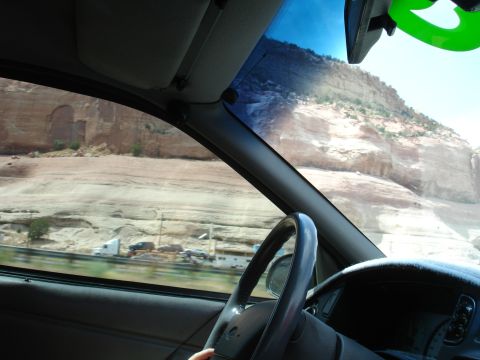 1993 Ford Taurus - Driving through a scenic desert landscape with rocky cliffs visible through the car window.
