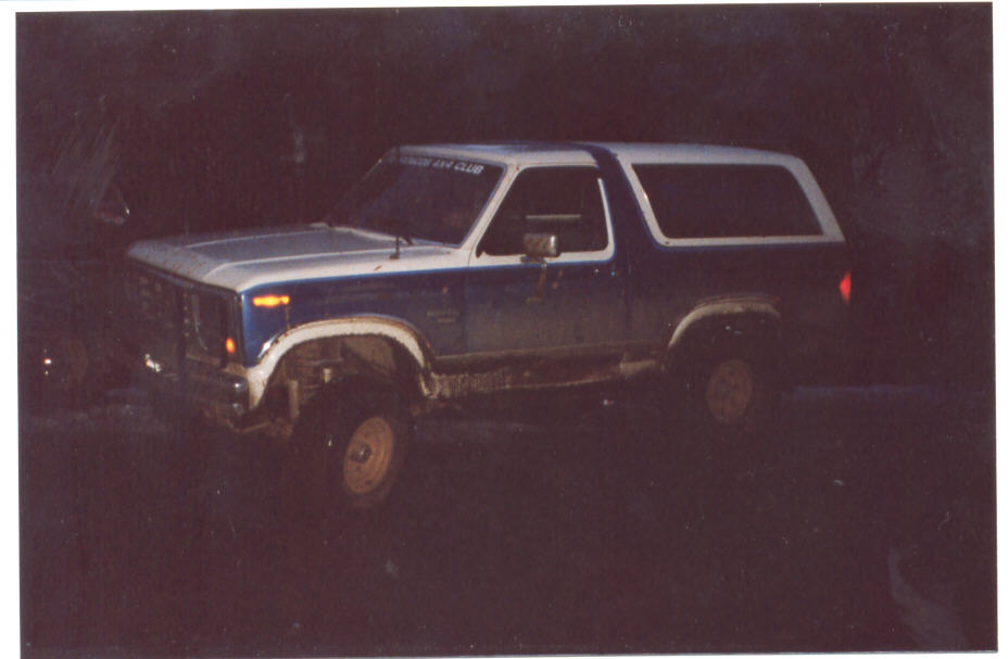 Two-tone blue Ford Bronco at night, lifted, 3q-front driver side