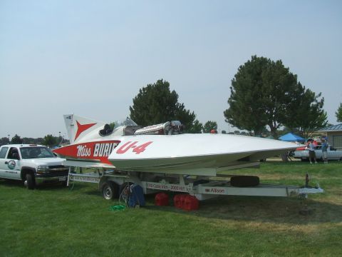 1974 Ford Ranchero - A white pickup truck is parked next to a white racing boat on a trailer on a grassy field.