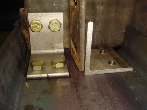 1996 Ford Bronco - Close-up view of metal brackets and bolts attached to a rusty frame, likely part of an aftermarket modification.