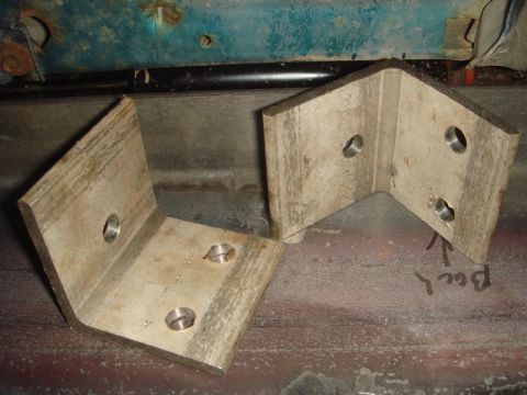 1996 Ford Bronco - Two custom metal L-brackets are shown installed on a vehicle frame, possibly for a winch mount. Text indicates the rear direction.