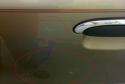 2007 Mercury Grand Marquis - Scratches are visible on the side of a gold car door, with a chrome handle and red pinstripe detail.