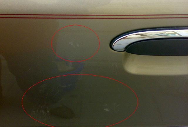 Gold car door with red pinstripe and chrome handle, showing multiple scratches circled in red