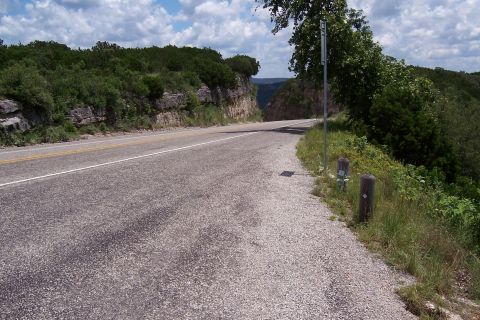 2003 Suzuki Bandit S - A scenic view of a road curving through a natural landscape with rocky cliffs and dense vegetation.