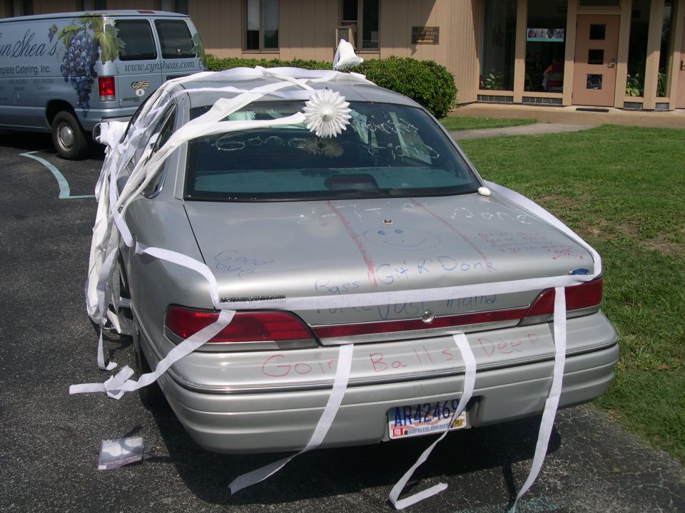Silver sedan decorated with streamers and writing for a wedding