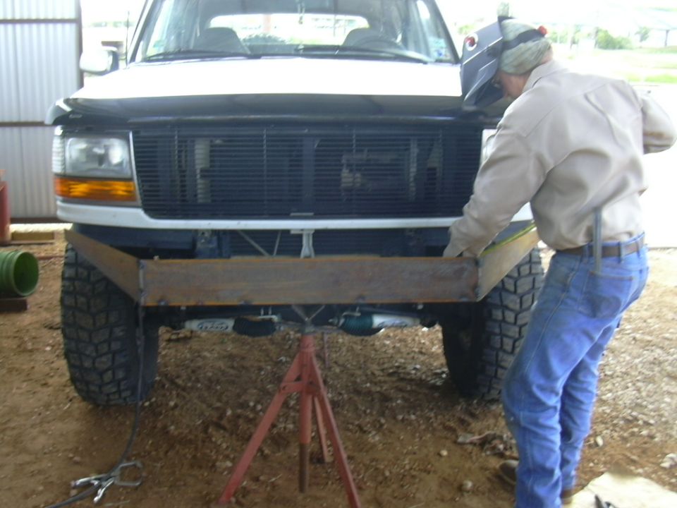 1995 Ford Bronco front end with a man welding a custom bumper