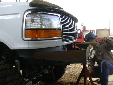 1995 Ford Bronco - A person is fabricating a custom bumper for a white Ford truck.