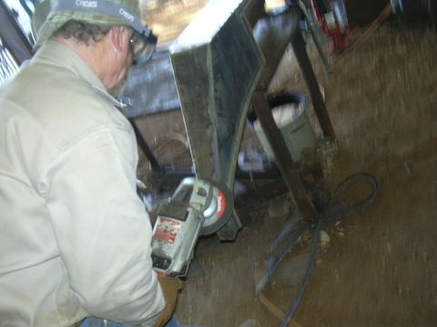 1995 Ford Bronco - A person is using an angle grinder on a metal object in a workshop setting.