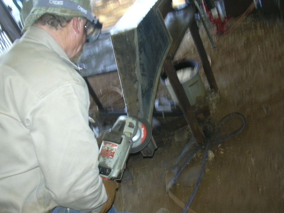 Man in tan shirt and hat grinding metal with an angle grinder