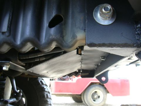 1995 Ford Bronco - Close-up of vehicle undercarriage, with a red cart in the background.