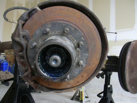 1995 Ford Bronco - Close-up of a vehicle's front axle hub and brake components, showing a greased hub and a rusty rotor.