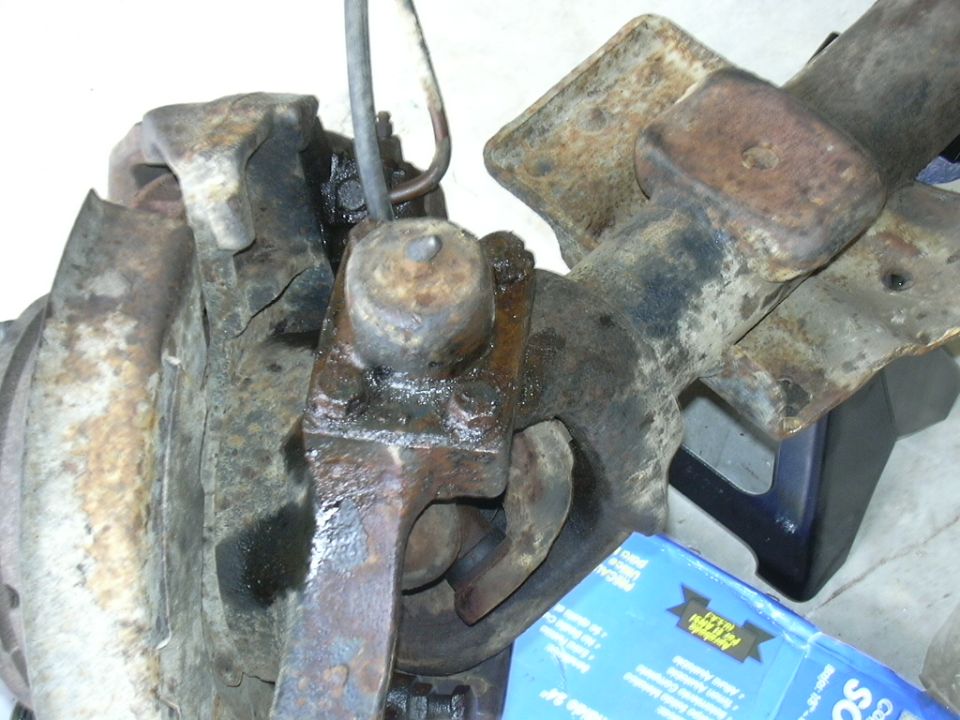 Rusty differential housing with suspension parts and Supermotors.net logo visible