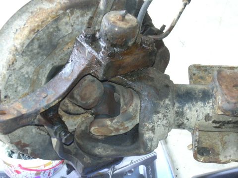 1995 Ford Bronco - Close-up view of a heavily corroded vehicle front axle assembly and its components.