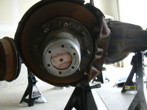 1995 Ford Bronco - Close-up of a vehicle's front axle hub and brake assembly, supported by jack stands.