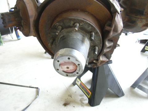 1995 Ford Bronco - The front wheel hub assembly, showing the locking mechanism and brake rotor, is supported by jack stands.