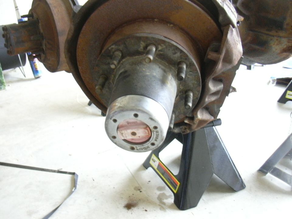Close-up of a vehicle's front wheel hub with a locking mechanism, resting on jack stands