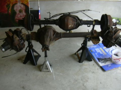 1995 Ford Bronco - Two vehicle axles are displayed on jack stands, suggesting they are parts for a vehicle modification or repair.