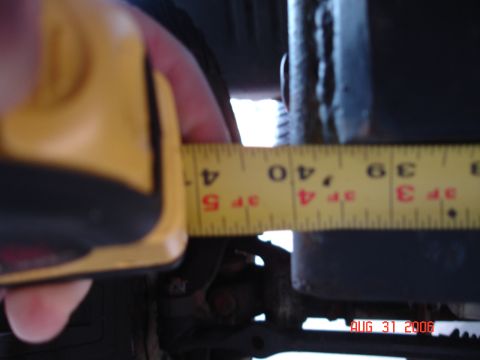 1995 Ford Bronco - A yellow tape measure is used to measure a suspension component on a vehicle.