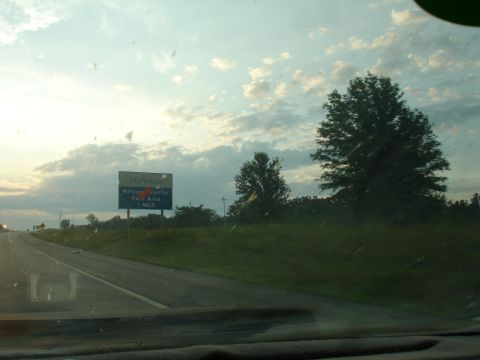 1993 Ford Taurus - A sign indicates a welcome center and rest area is one mile ahead on the highway.