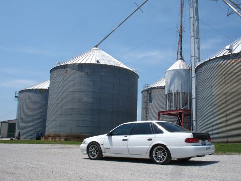 1993 Ford Taurus - White 1993 Ford Taurus SHO parked on gravel in front of industrial grain silos under a clear blue sky.